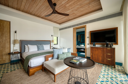 Luxuriöses Hotelzimmer mit großem Bett, Holzdecke mit Deckenventilator, Sitzbank und rundem Tisch in Sri Lanka