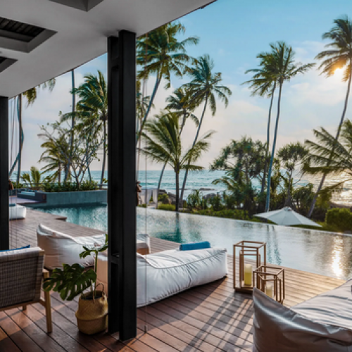 Luxuriöses Boutique-Hotel mit Infinity-Pool und Liegen auf Holzdeck, Palmen und Meerblick in Sri Lanka