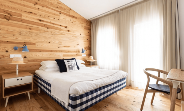 Hotelzimmer im Craverial Farmhouse mit Holzverkleidung, Doppelbett mit gestreiftem Bettlaken, Nachttischen, Tischlampe und einem Holzstuhl.