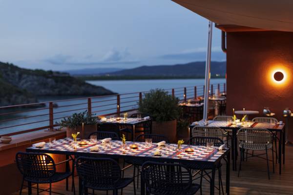 Außenrestaurant mit gedeckten Tischen auf der Terrasse eines Hotels mit Blick auf das Meer bei Dämmerung