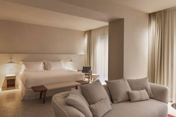 Junior Suite im Hotel Ercoletto mit großem Doppelbett, zwei Nachttischen, Sofa und großen Fenstern mit Vorhängen