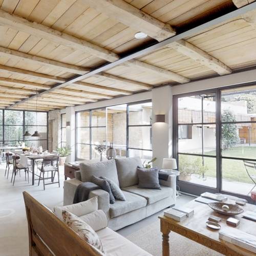 Lichtdurchfluteter Hotel-Loungebereich mit Sofas, Holztisch und großen Fenstern mit Blick auf Terrasse und Garten