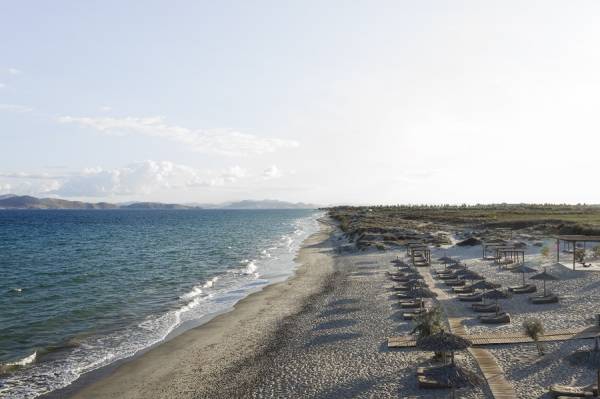 Strand mit Reihen von Liegestühlen und Sonnenschirmen am Hotel auf Kos, Blick auf das Meer und entfernte Berge