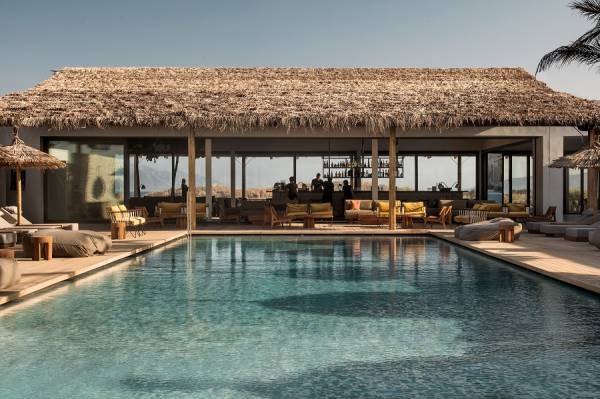 Hotel mit großem Pool und überdachtem Lounge-Bereich mit Sitzmöbeln, dargestellt auf der Website eines Reisebüros