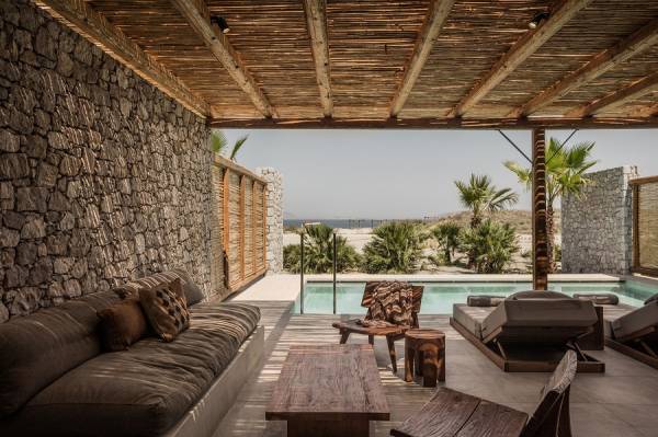Überdachte Lounge mit Sofa, Sesseln und Holztisch, Blick auf Pool und Palmen im Hotel auf Kos