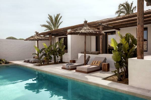 Hotelterrasse mit Pool, Liegen und Strohdächern, umgeben von tropischen Pflanzen