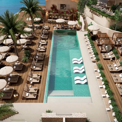 Hotelpool mit rechteckigem Becken, Liegestühlen und Sonnenschirmen auf Holzdeck, Palmen und Meerblick im Hintergrund