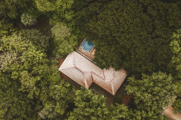 Vogelperspektive auf die Deluxe Villa, umgeben von dichtem Wald mit einem kleinen Pool neben dem Gebäude