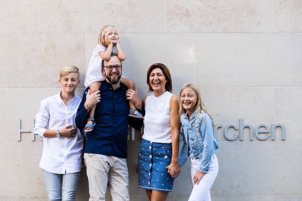 Eine Familie steht vor der Hotelanlage 'Storchen'. Der Mann tr&auml;gt ein Kind auf den Schultern, w&auml;hrend die anderen Familienmitglieder daneben stehen. Die Frau h&auml;lt die Hand eines M&auml;dchens.